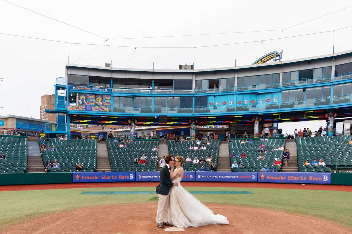 bride and groom on home plate at a baseball stadium